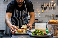 chef plating a sandwich in the kitchen